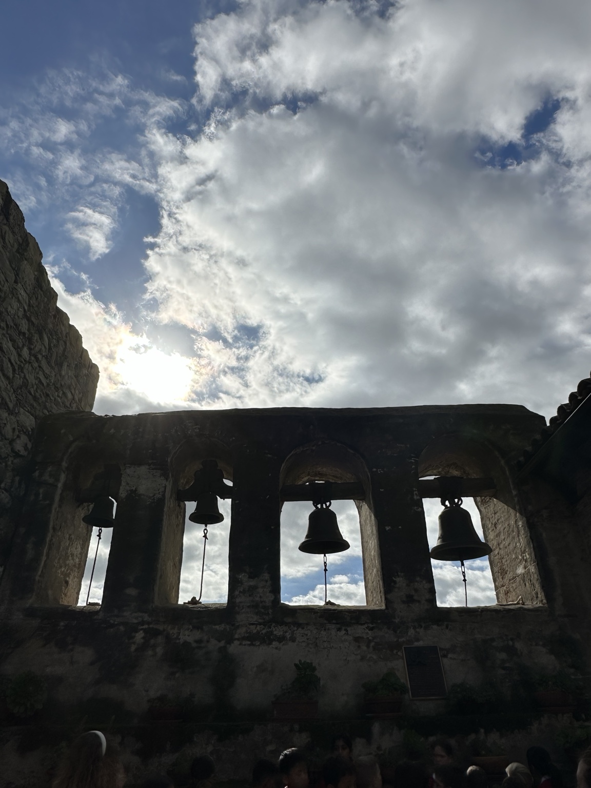 Mission San Juan Capistrano bells silhouetted beneath a dramatic sky